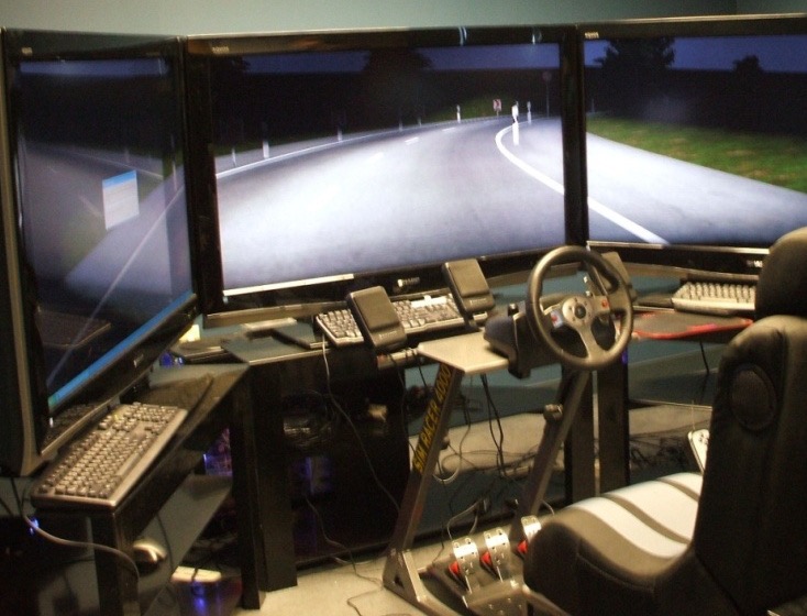 The VR driving simulator: triple screens, wheel, and seat running a night-road scene